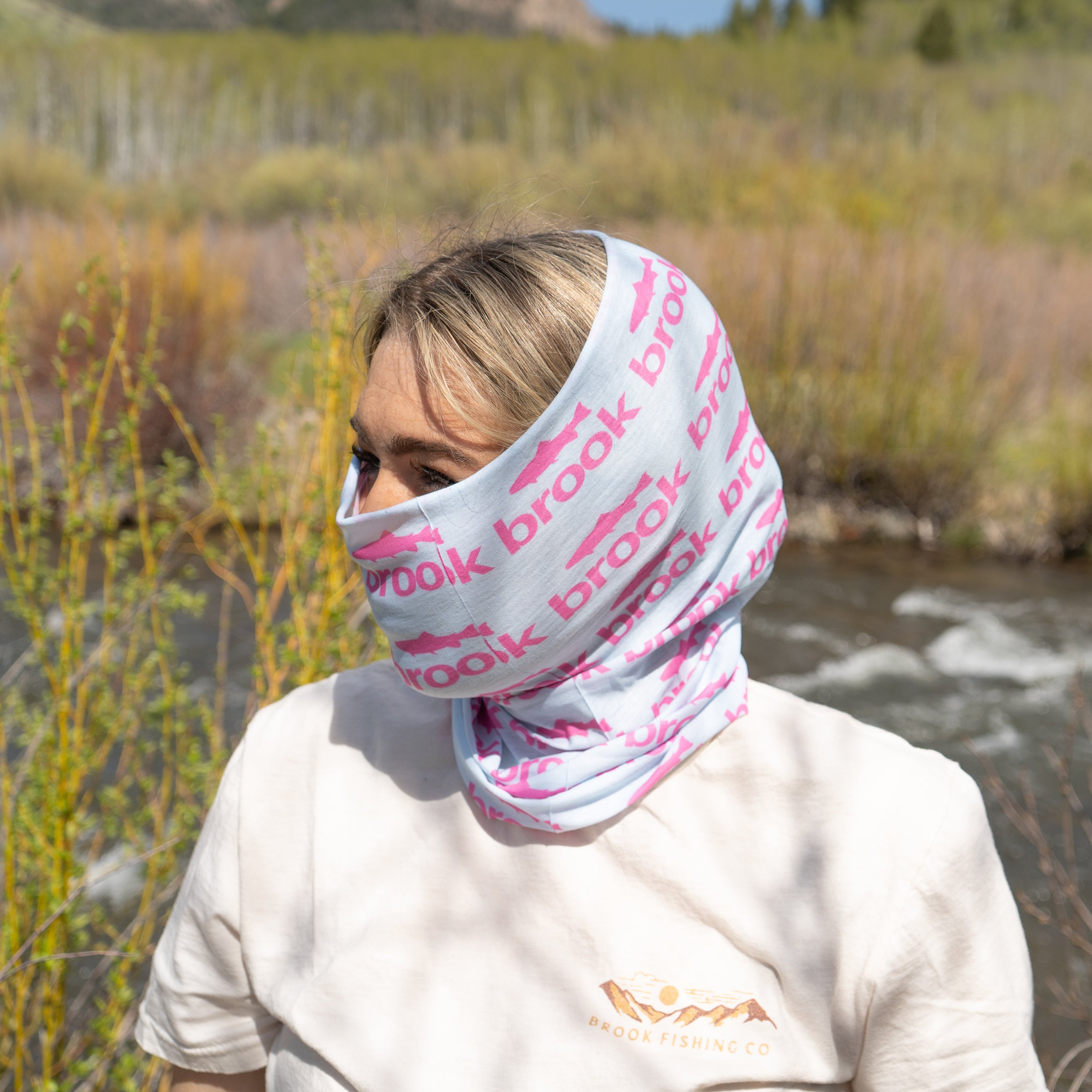 Person wearing a branded neck gaiter in a natural setting