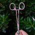 Close-up of Brook Floral Hemostats showing stainless steel build and pink floral pattern, designed for women anglers.