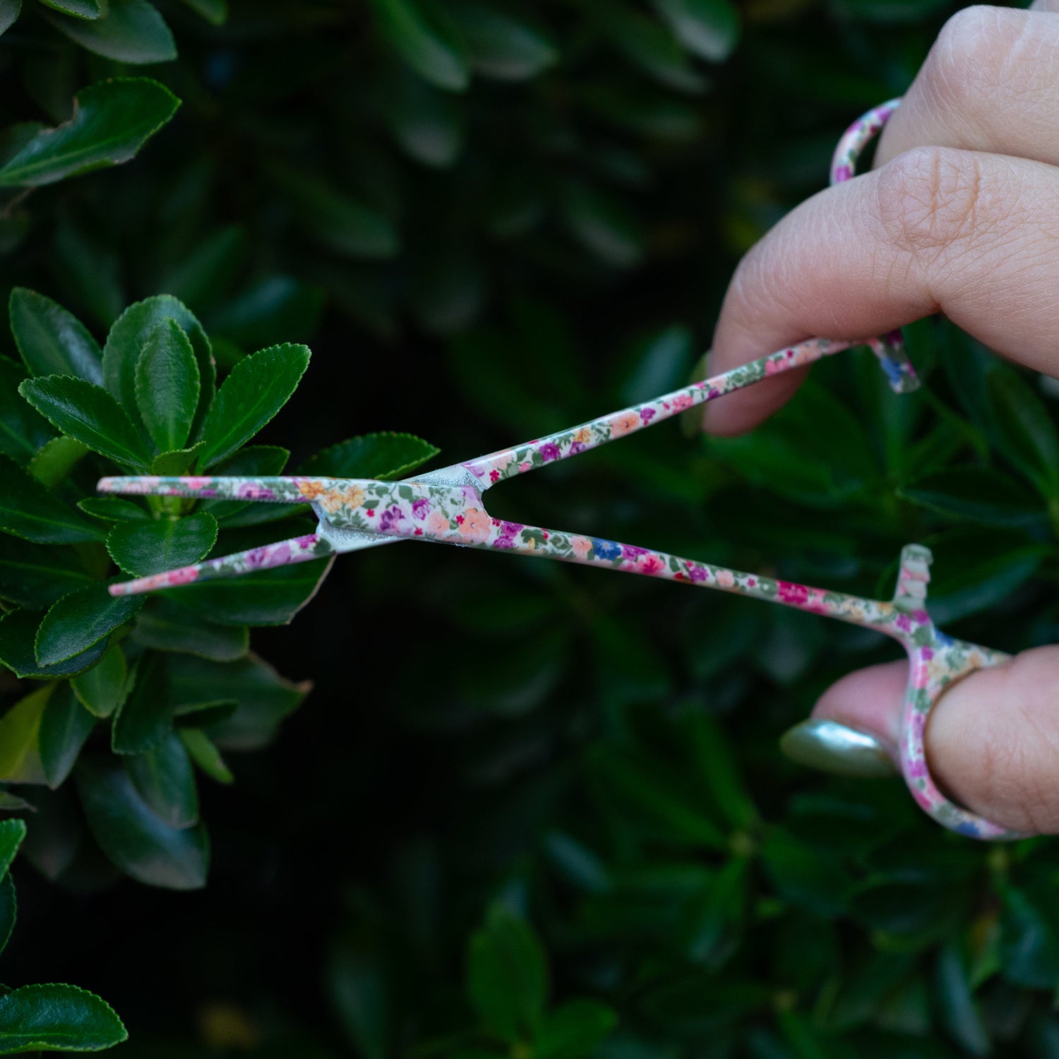 Hand opening Brook Floral Hemostats to show the wide grip and precise stainless steel tips with floral pattern design for women anglers.