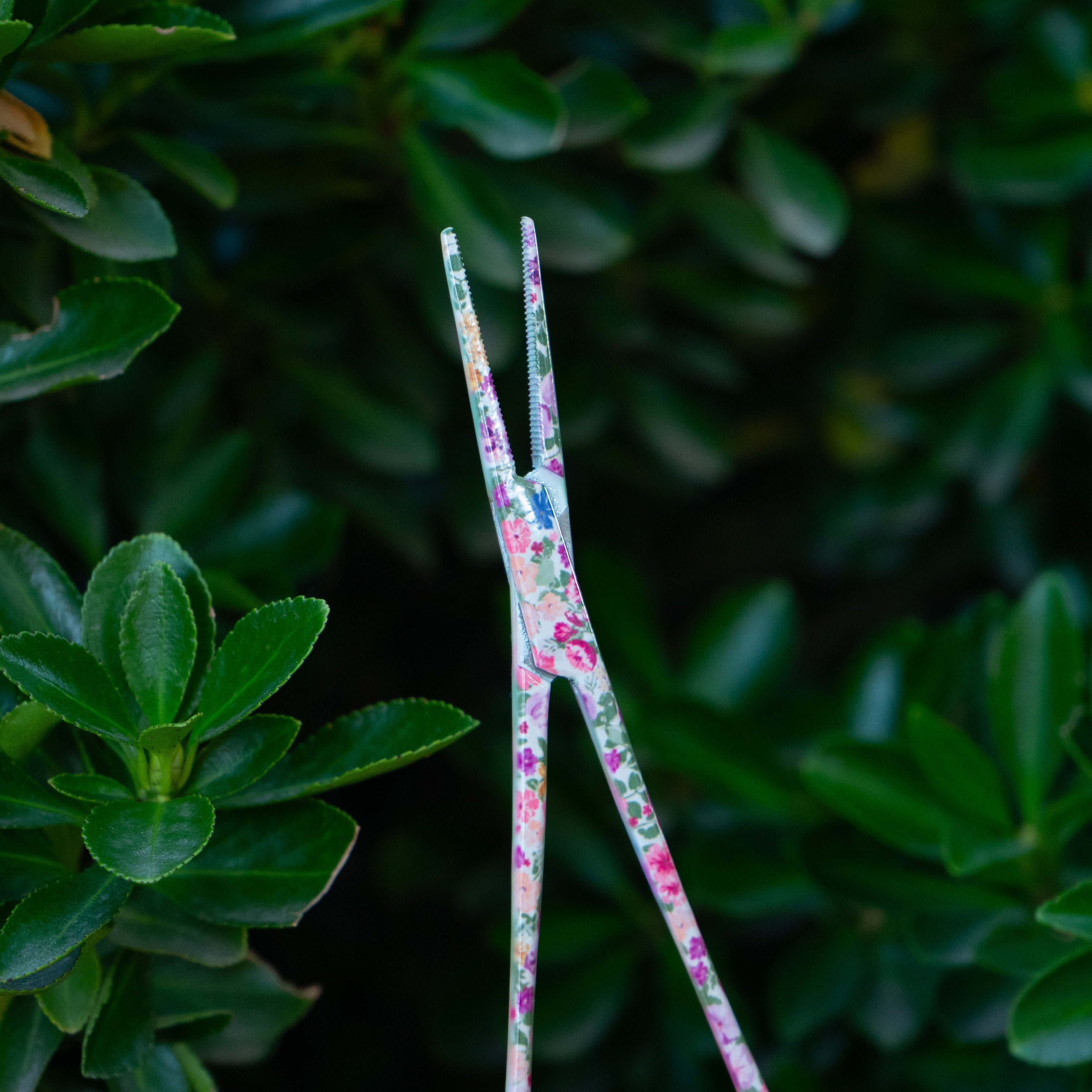 Close-up of the tip of Brook Floral Hemostats showing the serrated teeth and precise stainless steel grip with pink floral pattern for fly fishing.