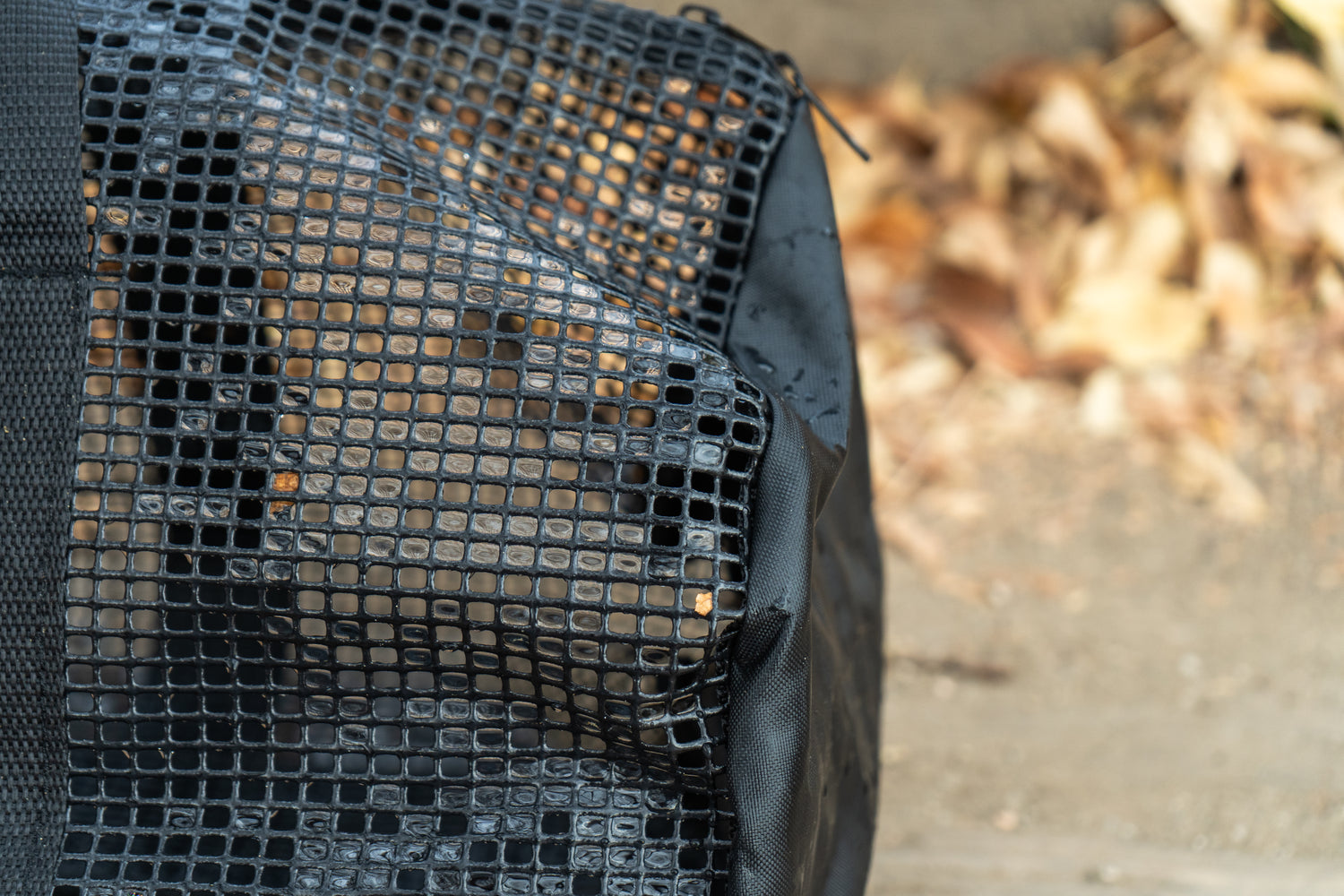 “Close-up of the black PVC mesh on the Brook Fishing Co. gear bag, showing the breathable grid texture with fallen leaves blurred in the background.”