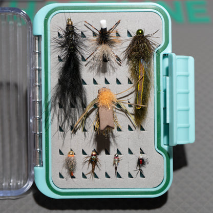 Collection of fly fishing lures in a box on a gray background