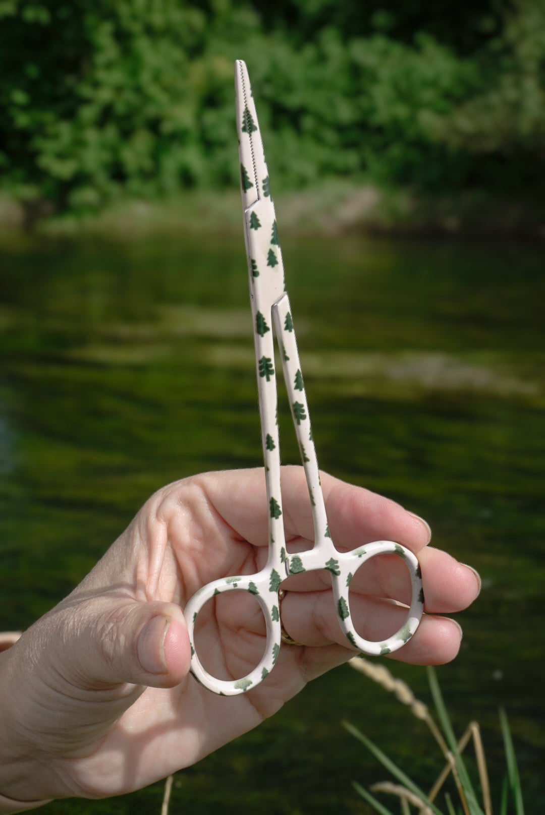 Patterned fly fishing hemostats featuring a tiny pine tree design. Built for easily removing hooks, pinching barbs, and handling flies on the water. A practical piece of fly fishing gear with a little more personality.